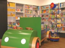Zu den Annehmlichkeiten im Geschäft gehört auch ein Kinder-Spielauto, welches gleichzeitig als Warenträger für Bilderbücher eingesetzt werden kann.